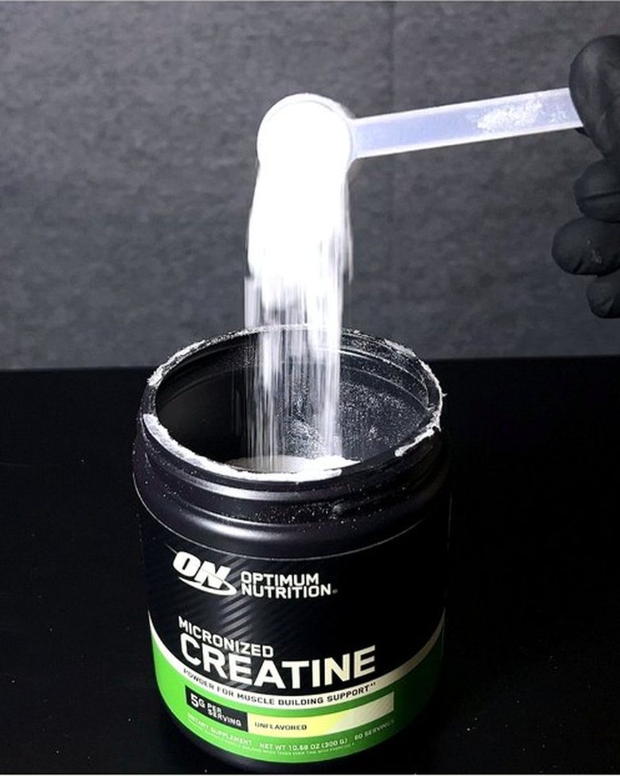 Polvo de creatina micronizada cayendo del scoop al tarro
